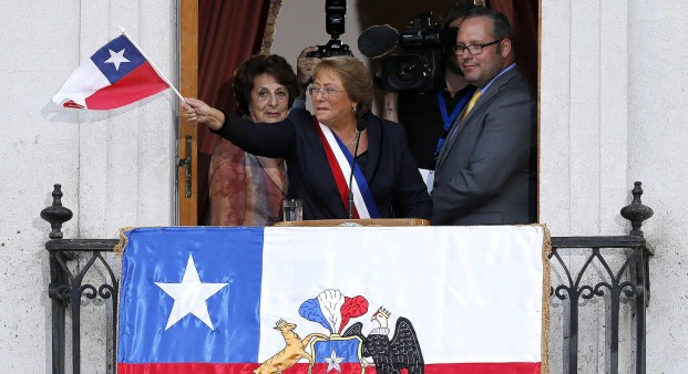 Chile's new president Michelle Bachelet waves a Chilean flag from a balcony of the La Moneda presidential palace after being sworn into office, in Santiago